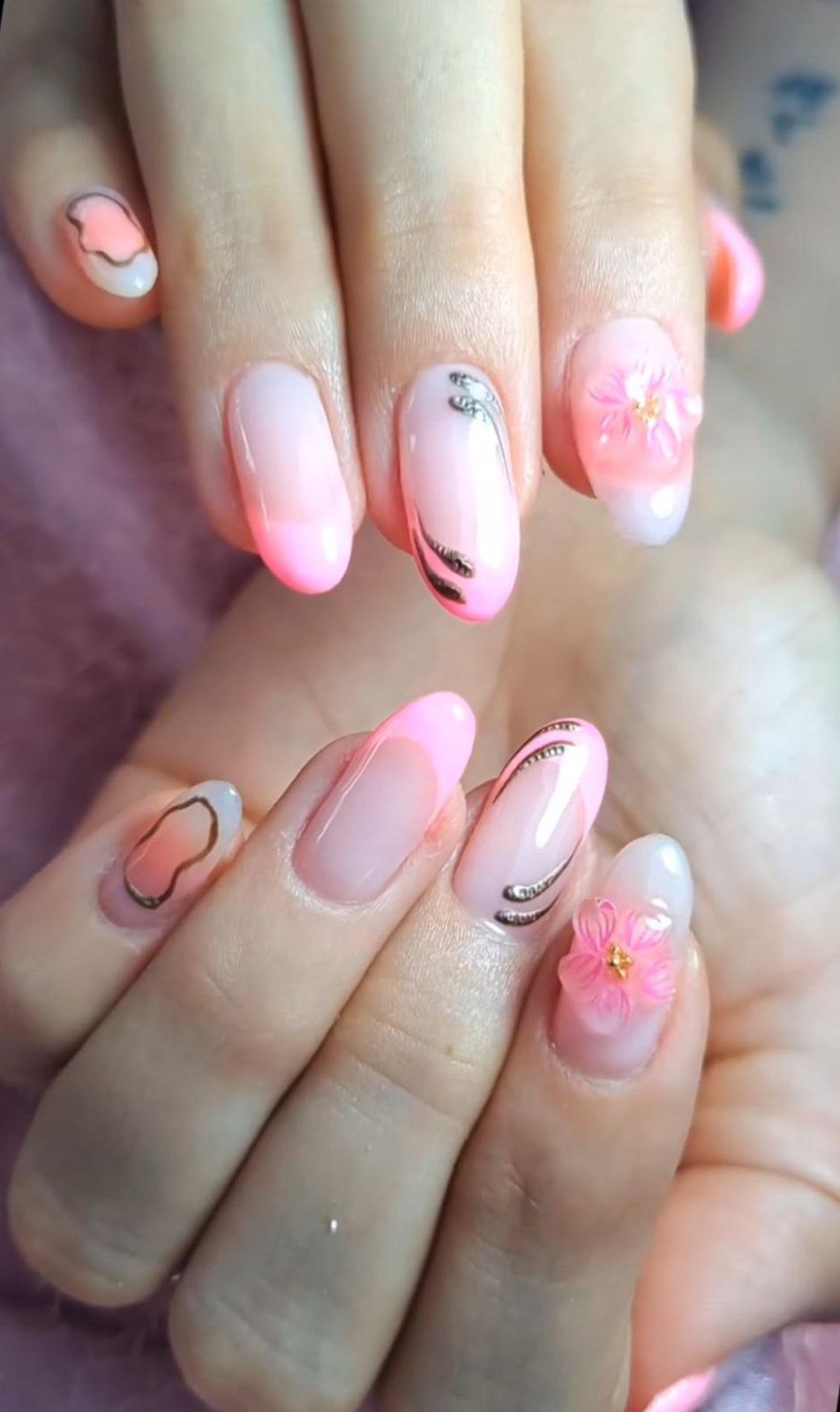 Uñas almendradas en degradado rosa con flores en relieve y líneas finas en negro